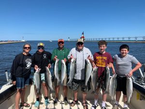 Fishing charter group holding up their salmon.